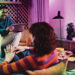 a woman sitting on a couch looking at a man using a laptop